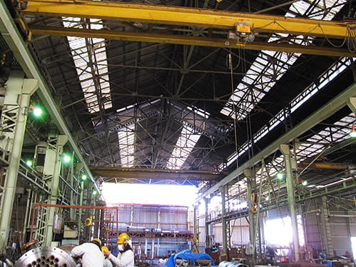 各種設備が置かれた本社工場内で機器製造を行う従業員